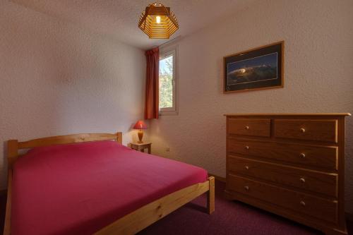 Un dormitorio con una cama y una cómoda y una ventana. en Vacancéole - Résidence Côte Brune, en Les Deux Alpes