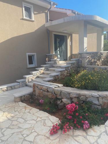 a house with a stone retaining wall and stairs at Lučica 360 sea view suite in Nerezine