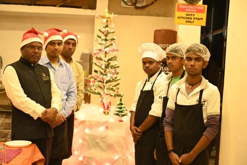 Grupa kucharzy stojąca przed choinką świąteczną w obiekcie Hotel Comfort and Terrace Lounge w mieście Deoghar