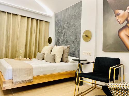 a bedroom with a bed and a chair and a painting at Canaryislandshost l The Secret Suites in Playa Honda