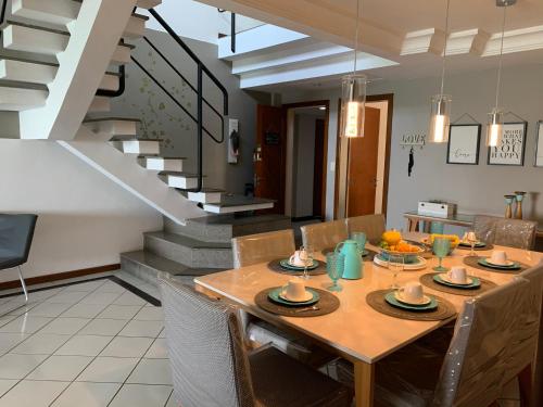 a dining room with a table and a staircase at Cobertura Duplex Beira Mar Praia do Morro, Guarapari in Guarapari