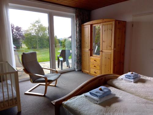 ein Schlafzimmer mit einem Bett, einem Stuhl und einem Fenster in der Unterkunft Ferienwohnung Kraniche am Krakower See in Kuchelmiß