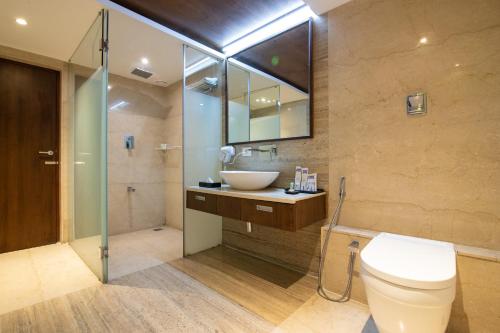 e bagno con servizi igienici, lavandino e doccia. di Bhagini Icon Premier Hotel a Bangalore