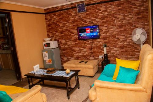 a living room with two couches and a tv on a brick wall at The White Dove - in Milimani Kisumu in Kisumu