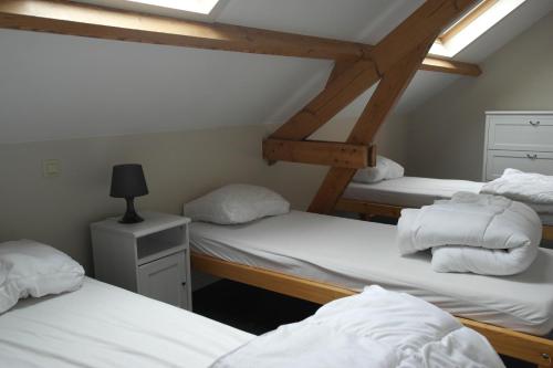 a room with three bunk beds with white sheets at De Lanterfanters Vakantiehuisjes in Nieuwpoort