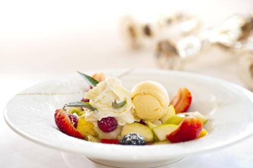 a bowl of fruit salad with ice cream and berries at Appartements-Restaurant Schwaiger in Tauplitz