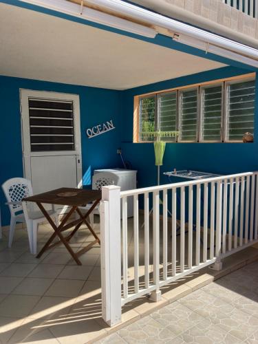 balcón con mesa y pared azul en Bas de villa Vacances Océan en Le Carbet