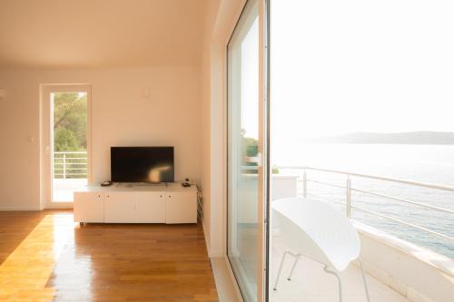 a living room with a television and a white chair at Vila Visnjic in Grebaštica