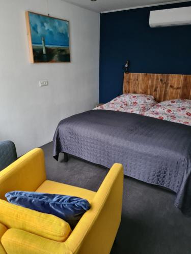 een slaapkamer met een bed en een gele stoel bij De Stoof, complete studio voor 2 personen in Renesse