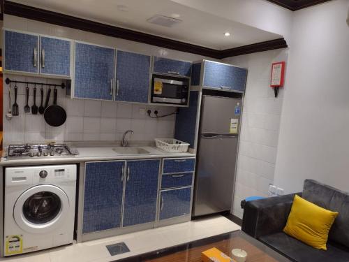 a kitchen with blue cabinets and a washer at Deyala Serviced Apartments 1 in Riyadh