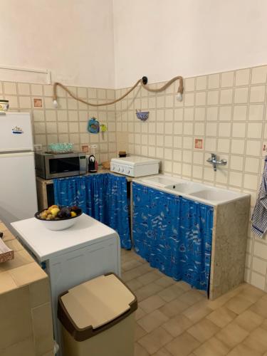 a kitchen with blue curtains and a bowl of fruit on a counter at La maison du vent in Marettimo