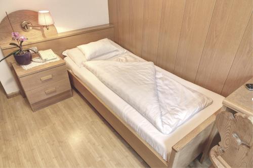 a small bed in a small room with a night stand at Hotel & Residence Sylvanerhof in Chiusa