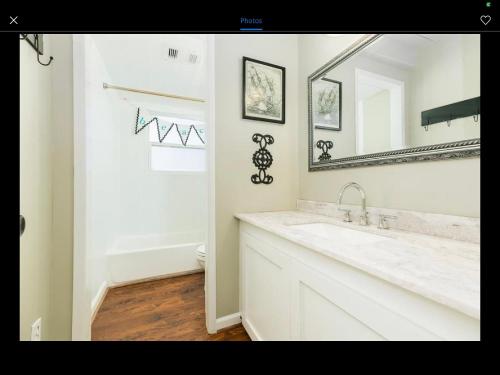 a white bathroom with a sink and a mirror at Salty Poodle Cottage in Freeport