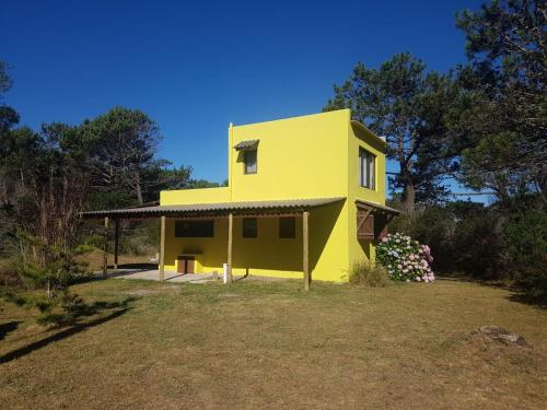 a yellow house in the middle of a yard at Riyadh - en el bosque a metros de la playa in Rincón de los Oliveras