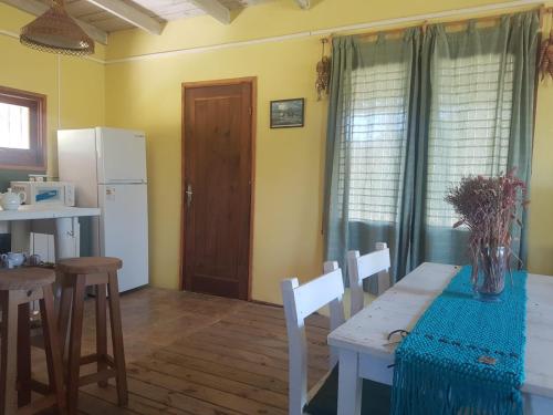 a kitchen with a table and chairs and a refrigerator at Riyadh - en el bosque a metros de la playa in Rincón de los Oliveras