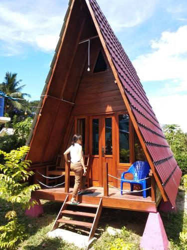 a woman standing in front of a small house at Tanjong Tinggi Cottage in Sijuk