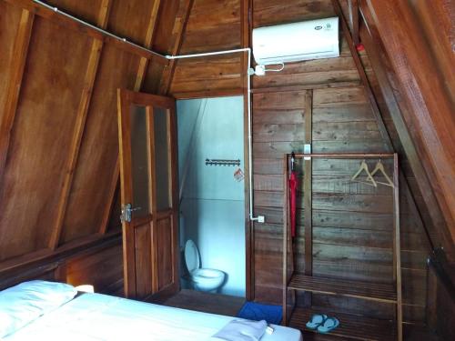 Mały pokój z łóżkiem i drewnianą ścianą w obiekcie Tanjong Tinggi Cottage w mieście Sijuk