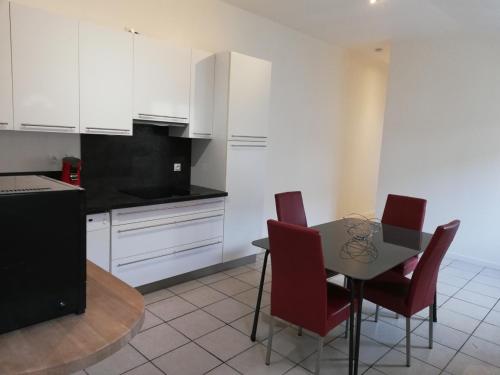 a kitchen with white cabinets and a table and chairs at logement entier au calme in Villers-Outréaux