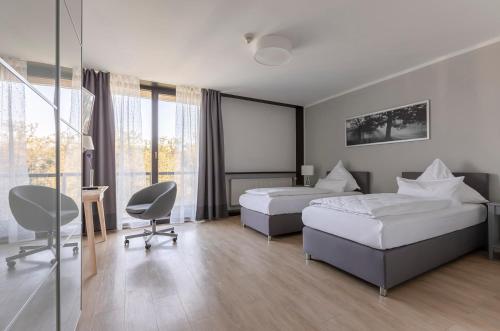 ein Hotelzimmer mit 2 Betten, einem Schreibtisch und Stühlen in der Unterkunft Bildungs- und Tagungshaus Haus Neuland in Bielefeld