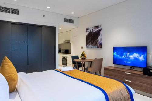 a bedroom with a large bed and a flat screen tv at SUHA Mina Rashid Hotel Apartments in Dubai