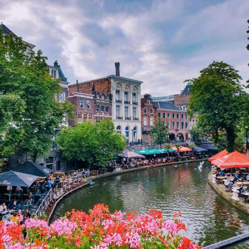 a river with a group of people sitting at tables next to a canal at Logement Petit Beijers in Utrecht