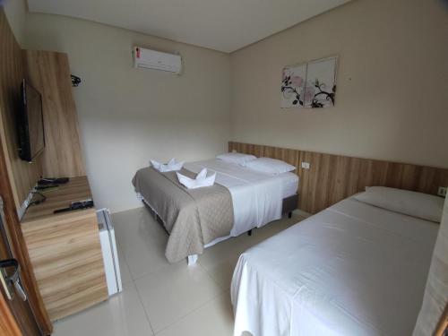a hotel room with two beds and a television at HOTEL POUSADA DAS ROSAS in Carolina