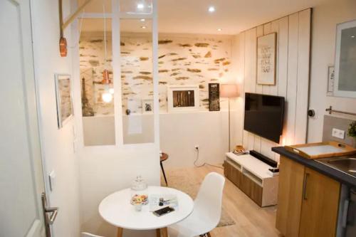 une petite chambre avec une table blanche et une cuisine dans l'établissement Gîte urbain ancienne écurie au centre ville et PARKING, à Nantes