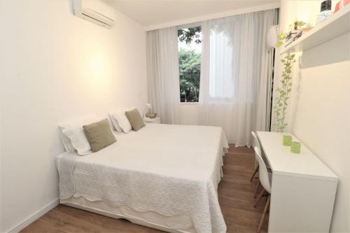 a white bedroom with a bed and a window at Leblon House IV in Rio de Janeiro