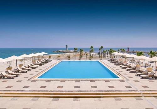 a pool with chairs and the ocean in the background at Steigenberger Hotel El Lessan in Ras El Bar