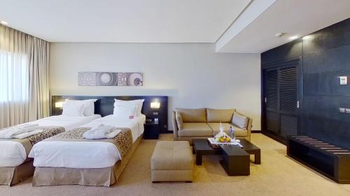 a hotel room with two beds and a couch at Mövenpick Hotel Casablanca in Casablanca