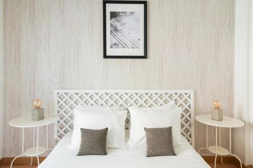 a bedroom with a white bed with two tables at Casa do Ar in Sesimbra