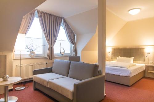 Hermes Hotel Oldenburg في أولدنبورغ: غرفة نوم بسرير واريكة ونافذة
