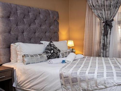 a bedroom with a large bed with a large headboard at Belz Boutique Hotel in Ixopo