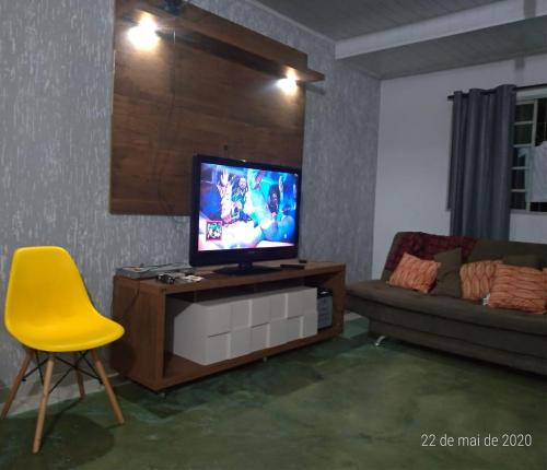 a living room with a television and a yellow chair at Villa Flor e Cor in Cavalcante