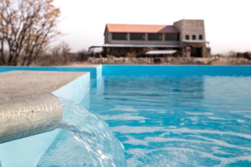una piscina con una manguera de agua frente a un edificio en Etosha Trading Post Campsite, en Okaukuejo