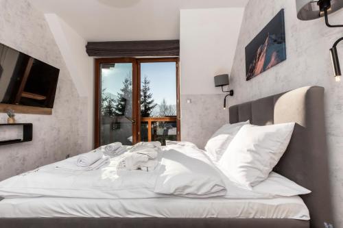 a white bed in a room with a window at Tatra Resort & SPA in Kościelisko