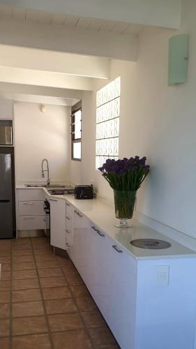 a kitchen with a vase of purple flowers on a counter at Villa Vista in Mossel Bay