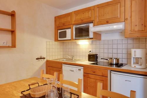 - une cuisine avec des placards en bois et une table en bois avec une table dans l'établissement Vacancéole - Résidence Les Bleuets, à Les Deux Alpes