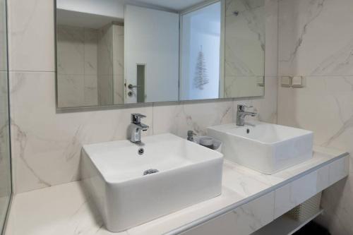 ein weißes Badezimmer mit zwei Waschbecken und einem Spiegel in der Unterkunft HH Bluewater in Logaras
