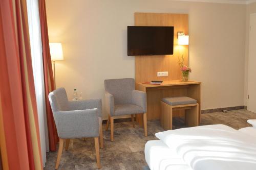 ein Hotelzimmer mit einem Schreibtisch, Stühlen und einem Bett in der Unterkunft Land-gut-Hotel Allerhof in Frankenfeld