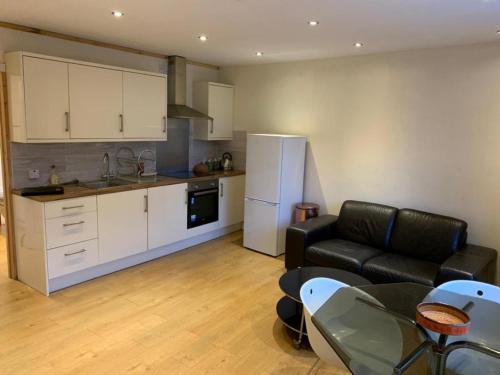 a kitchen and a living room with a couch and a table at 1-Bed unit 10 minute drive from Hellfire Caves in High Wycombe
