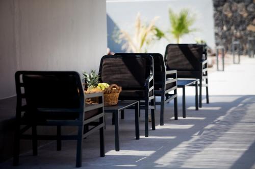 a row of chairs with a table with a basket on it at Terra Nera Suites in Perivolos