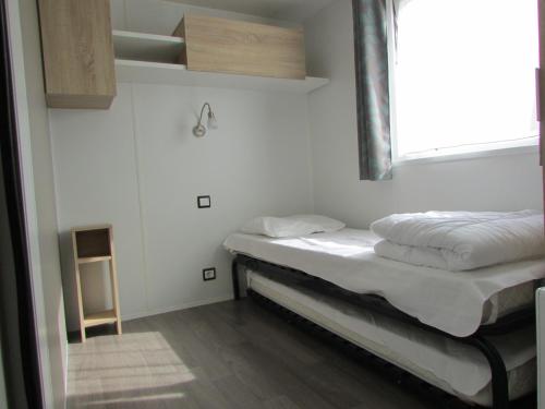 Cette petite chambre dispose d'un lit et d'une fenêtre. dans l'établissement Assist' Mobil Home 348 - mobil home 3 chambres tout confort, à Onzain