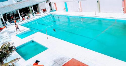 - une piscine d'eau bleue avec une personne dans l'établissement San Remo Resort Hotel, à Santa Teresita