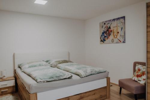 uma cama num quarto com uma cadeira e um quadro em Peter Lamster Top3 em Frauenkirchen