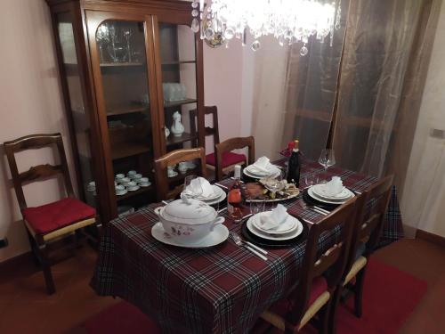 a dining room table with a chandelier and a table set with dishes at Casa Chiantishire in Montespertoli