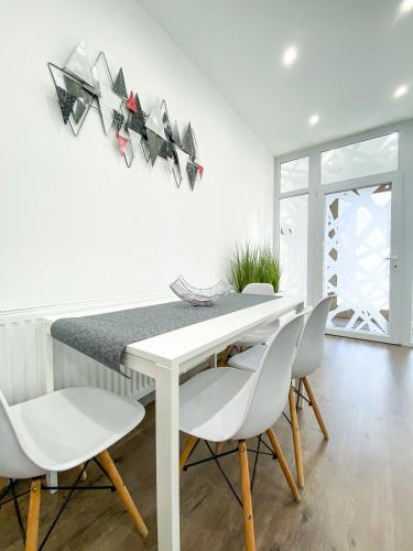 a white dining room with a white table and chairs at Főtér apartman II. in Villány