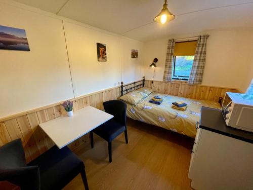 1 dormitorio con 1 cama, mesa y sillas en Per Ardua Shepherds Hut en Fort William