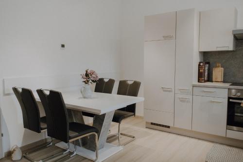 a white kitchen with a table and chairs at Peter Lamster Top1 in Frauenkirchen