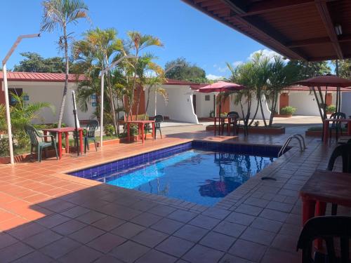 un complejo de piscina con mesas, sillas y palmeras en HOTEL CARISABEL en Aguadulce